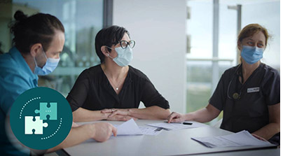 staff sitting around a table in masks